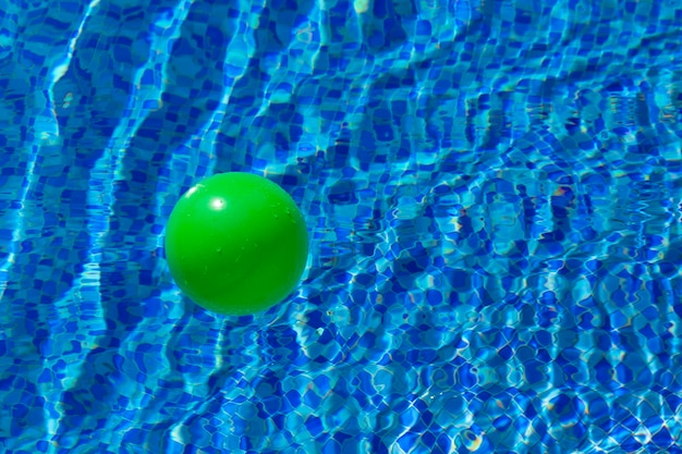 Palla verde rotonda sulla superficie dell'acqua in una piscina con acqua blu e onde Il concetto di sicurezza dei bambini vicino all'acqua