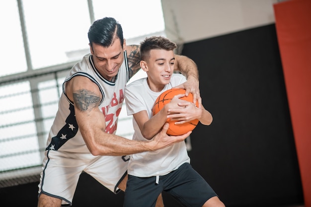 Pallacanestro. Uomo dai capelli scuri che gioca a basket con un ragazzo