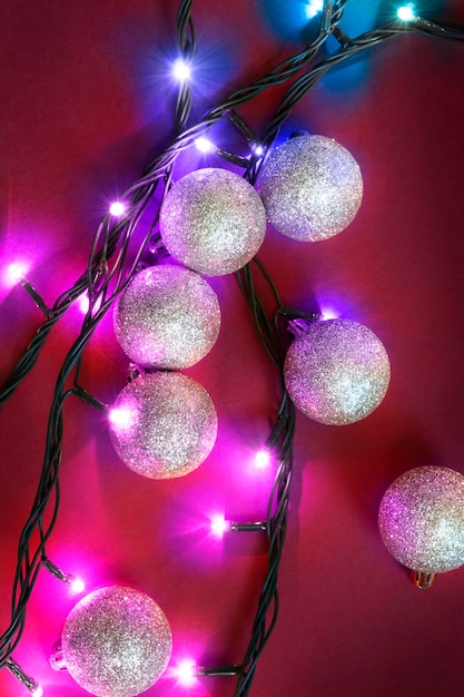 Palle di Natale d'argento e luci a led colorate su sfondo rosso