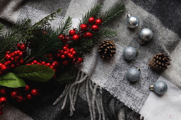 Palle di Natale di colore argento su un'accogliente coperta grigia con rami di pigne di albero di Natale