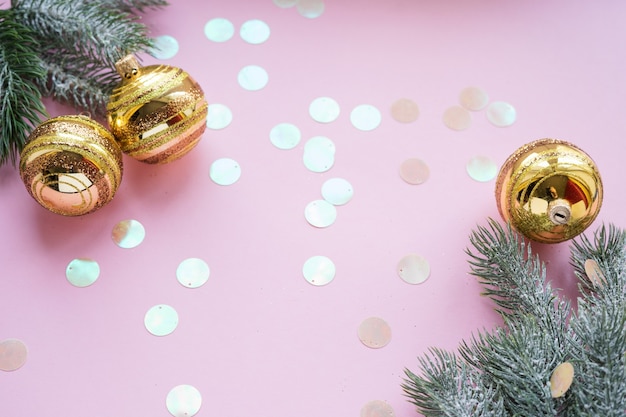 Palle di Natale dorate e rami di abete su sfondo rosa con spazio per le copie.