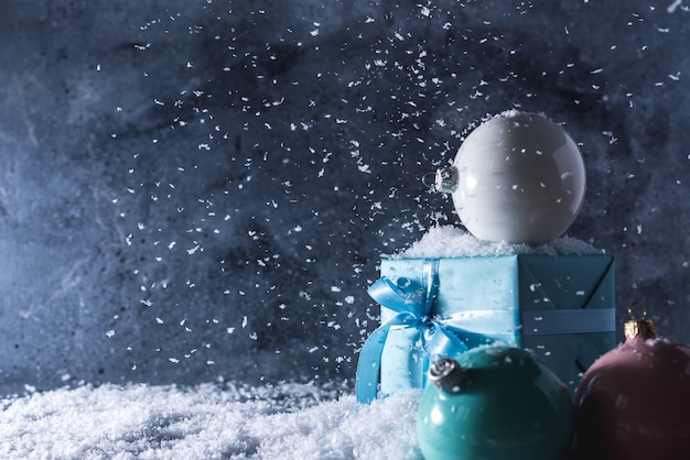 palle di Natale e confezione regalo su sfondo blu neve