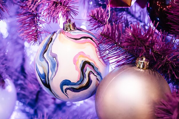 Palle di Natale e ghirlande luminose su un albero di Natale viola