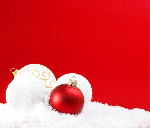 Palle di Natale e palle di neve su sfondo rosso