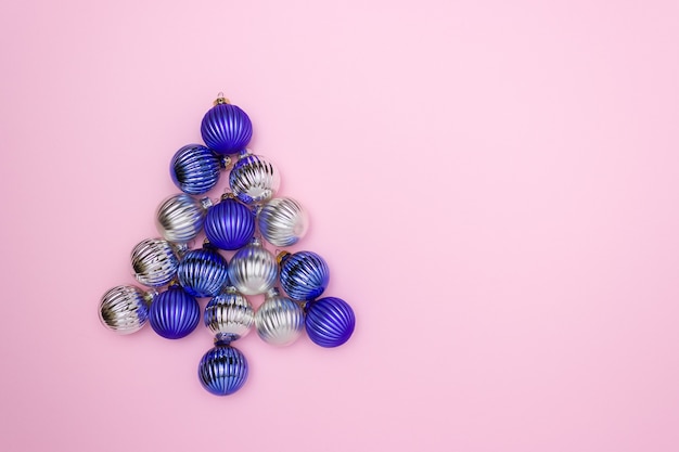 Palle di Natale per decorare blu e argento su uno sfondo rosa a forma di albero di Natale