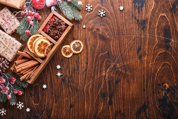 Palle di Natale rosse e verdi della decorazione dell'albero di abete, cannella sagomata e fette di arance secche su fondo di legno per i vostri auguri di Natale. Vista dall'alto con copia spazio. Biglietto di auguri di Natale.