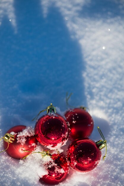 palle rosse di natale con lunghe ombre nella neve fresca in una bella giornata invernale di sole