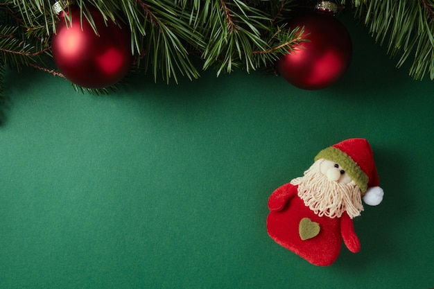 Palle rosse, rami di abete e Babbo Natale stracciato su sfondo verde. Copia spazio