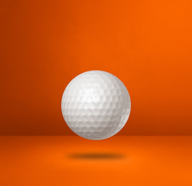 Pallina da golf bianca isolata su una priorità bassa arancione dello studio.