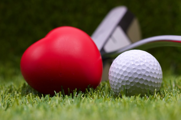 Pallina da golf con forma di cuore sull&#39;erba verde per amore e il concetto di San Valentino