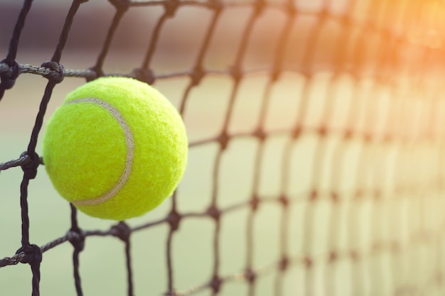 Pallina da tennis che colpisce alla rete sul fondo del campo da tennis della sfuocatura