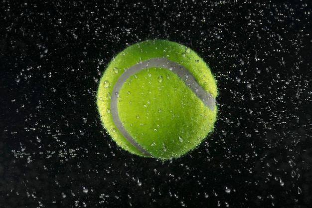 Pallina da tennis in acqua su uno sfondo scuro