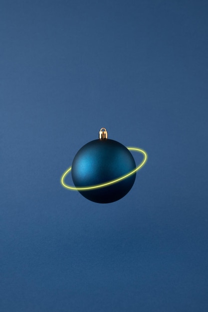 Pallina di Natale blu levitante isolata con anello di Saturno al neon su sfondo blu