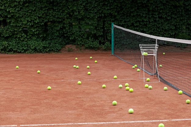 Palline da tennis sparse sul campo da tennis in terra battuta. Campo sportivo all'aperto. Addestramento. Messa a fuoco selettiva.