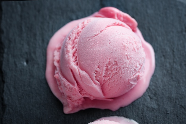Palline di gelato alla fragola alla frutta con salsa di fragole servite su piatto con frutta e pistacchi. Avvicinamento.