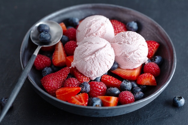 Palline di gelato alla fragola fruttate servite su piatto con frutta. Avvicinamento