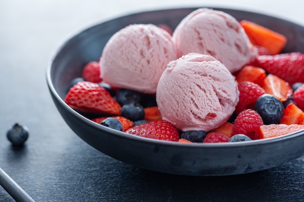 Palline di gelato alla fragola fruttate servite su piatto con frutta. Avvicinamento