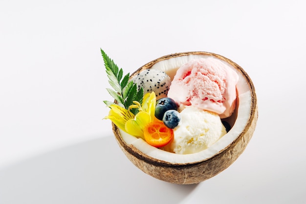 Palline di gelato decorazione fiori a metà di cocco. Concetto tropicale estivo.