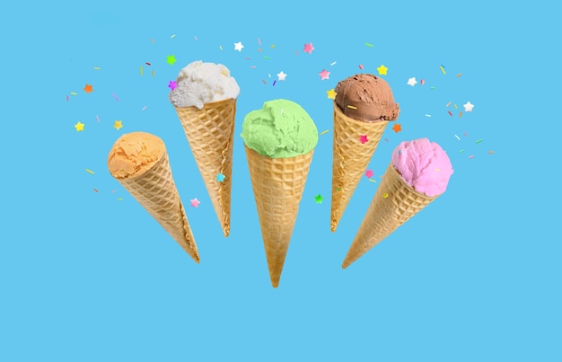 Palline di gelato in coni di waffle con granelli isolati su sfondo blu Sfondo di compleanno o di vacanza