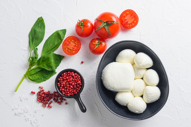 Palline di mozzarella crude mature con foglie di basilico fresco e pomodorini