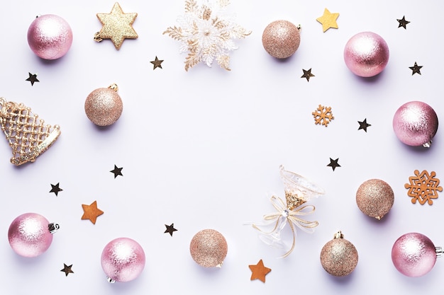 Palline di Natale, cornice di decorazioni dorate e rosa, coriandoli su sfondo pastello con spazio per le copie. Cartolina di Natale con ornamenti, vista dall'alto