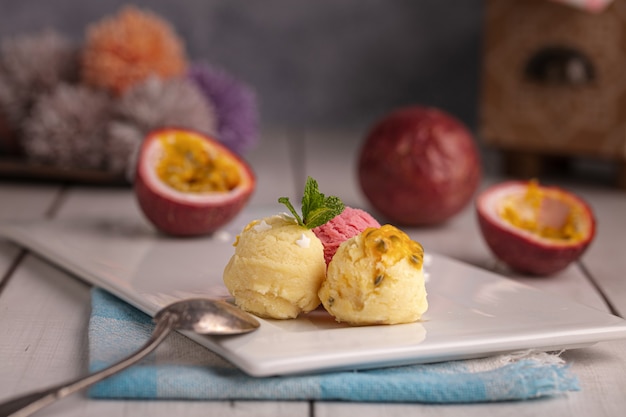 Palline di passione, gelato alla vaniglia e alla fragola su un piatto bianco su un tavolo di legno