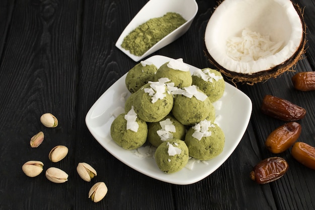 Palline energetiche con polvere di matcha, pistacchi, datteri e scaglie di cocco nel piatto bianco