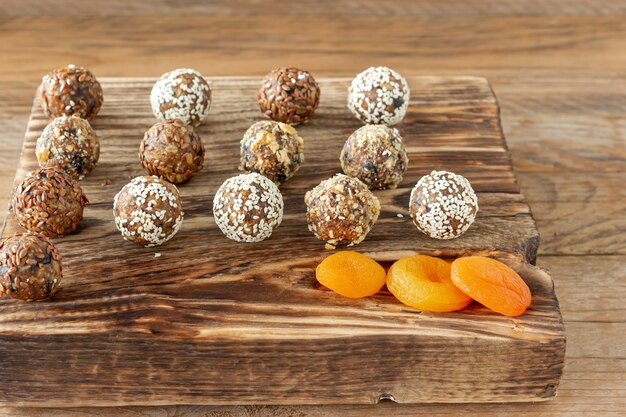 Palline energetiche fatte in casa con albicocche secche, uvetta, datteri, prugne, noci, mandorle e cocco su fondo di legno. Cibo dolce sano.