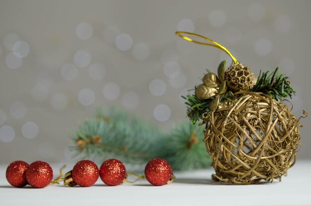 Palline rosse del ballnd di natale dorato di vimini sul fondo del bokeh