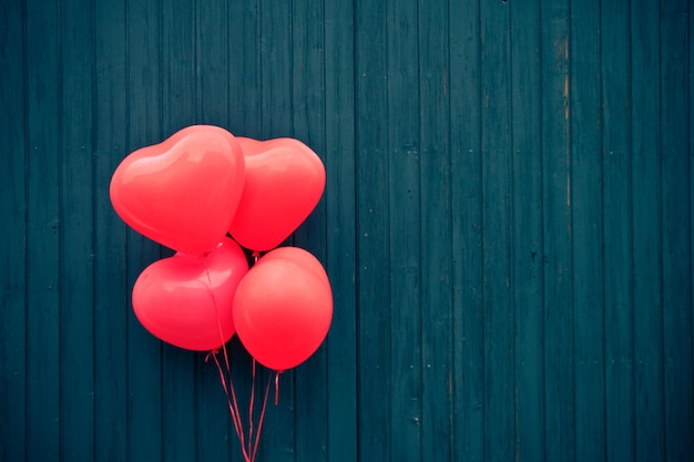 Palloncini a forma di cuore rosa contro una parete di legno blu