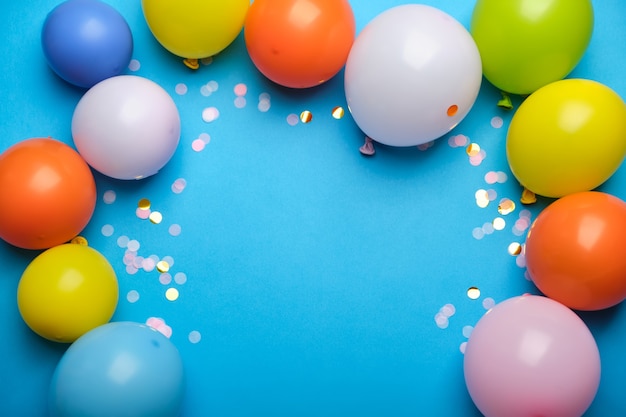 Palloncini colorati e coriandoli sulla vista del piano d'appoggio blu.