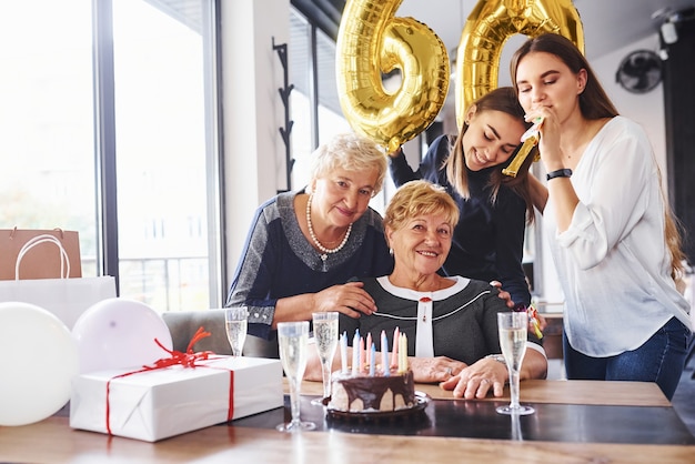 Palloncini con numero 60. Donna anziana con la famiglia e gli amici che festeggiano un compleanno in casa.