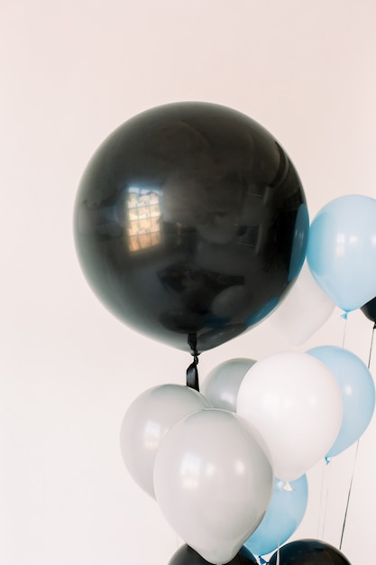 Palloncini neri, grigi, blu e bianchi su sfondo bianco. Concetto di celebrazione. Mongolfiere per una vacanza, festa di compleanno. Foto per poster o cartoline.