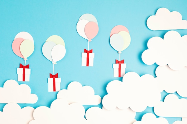 Palloncini Papercut e confezione regalo galleggianti nel cielo blu con nuvole