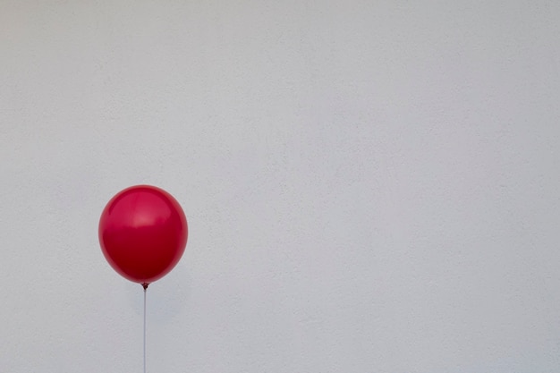 Palloncino rosso contro un muro bianco. Segno di depressione e ansia