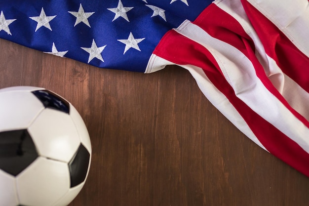 Pallone da calcio e bandiera americana su uno sfondo di legno.