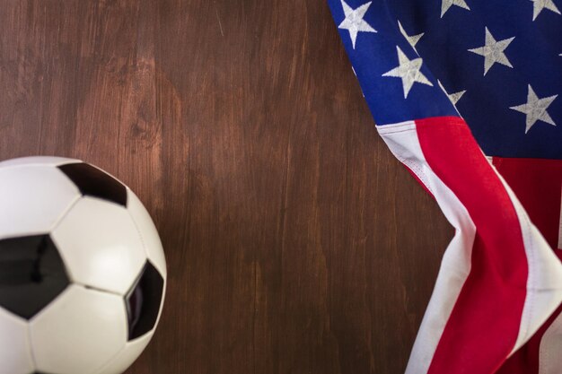 Pallone da calcio e bandiera americana su uno sfondo di legno.