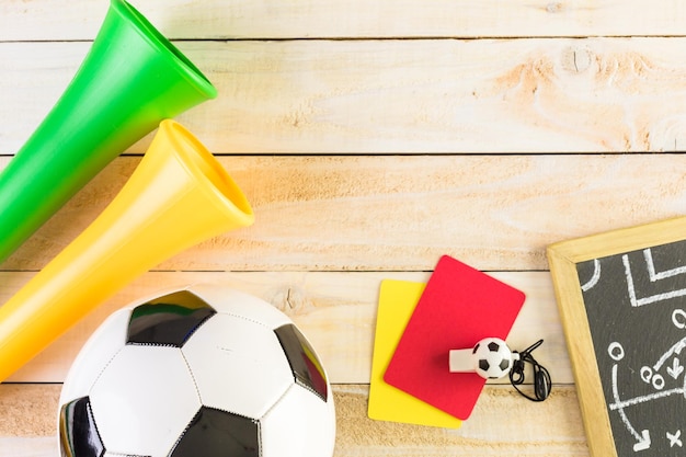 Pallone da calcio e corna dello stadio Vuvuzela su uno sfondo di legno.