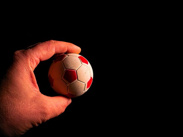 Pallone da calcio in mano su uno sfondo nero