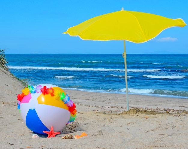 Pallone da spiaggia con collana e ombrellone in riva al mare