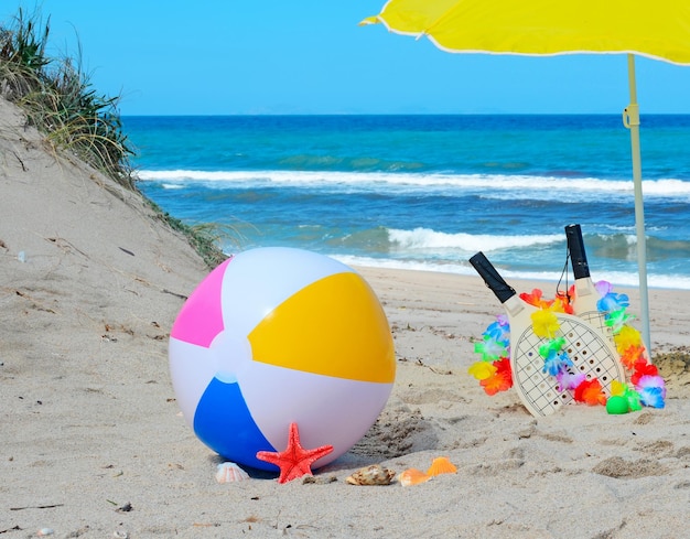 Pallone da spiaggia conchiglie stelle marine racchette e ombrellone in spiaggia