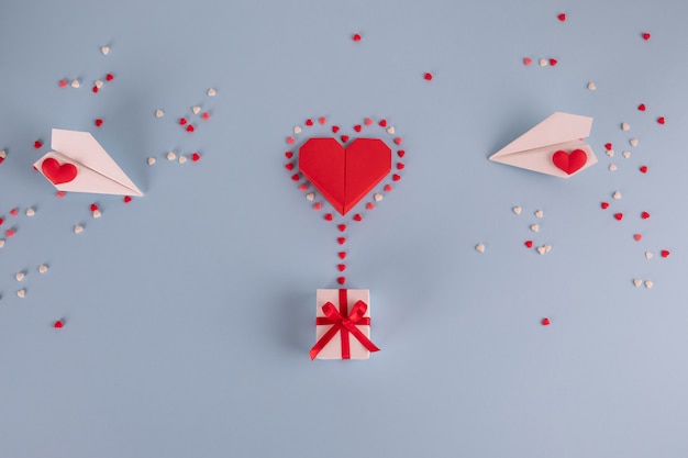 Pallone del cuore di carta di origami con il contenitore di regalo sulla tavola blu