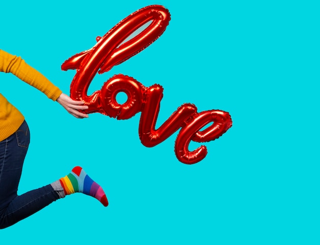 Pallone della tenuta della donna con i calzini di amore e dell'arcobaleno di parola