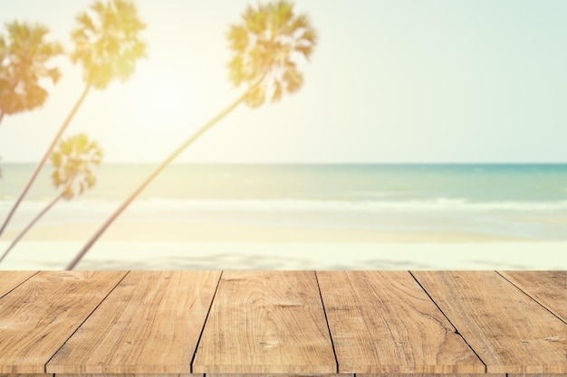 Palma della spiaggia del mare di estate con lo spazio del primo piano della tavola di legno per la tonalità di colore dell'annata del fondo del montaggio dei prodotti di pubblicità