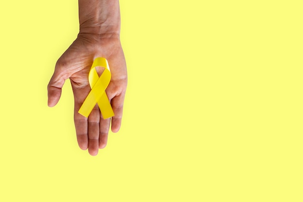 Palmo teso con nastro giallo della campagna di prevenzione del suicidio. Settembre giallo.