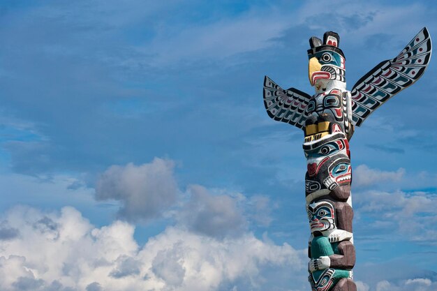 Palo di legno del totem nei precedenti nuvolosi blu