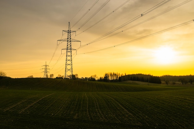 Palo elettrico ad alta tensione e linee elettriche di trasmissione al tramonto