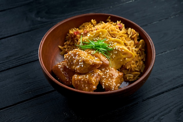 Pan-Asian Street Food - Pollo in agrodolce guarnito con riso, servito in una ciotola su uno sfondo di legno.