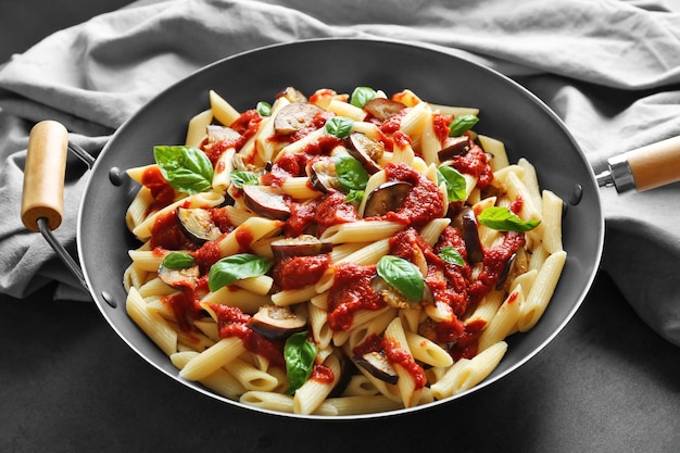 Pan con maccheroni basilico ketchup fette di melanzane e tovagliolo sul tavolo scuro