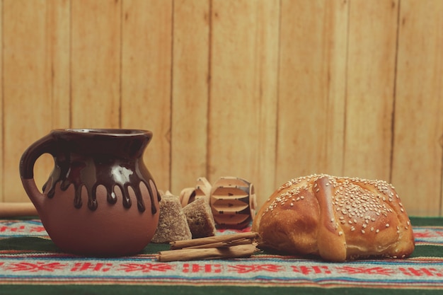 Pan de muerto y taza de chocolate sobre una mesa con mantel tpico mexicano